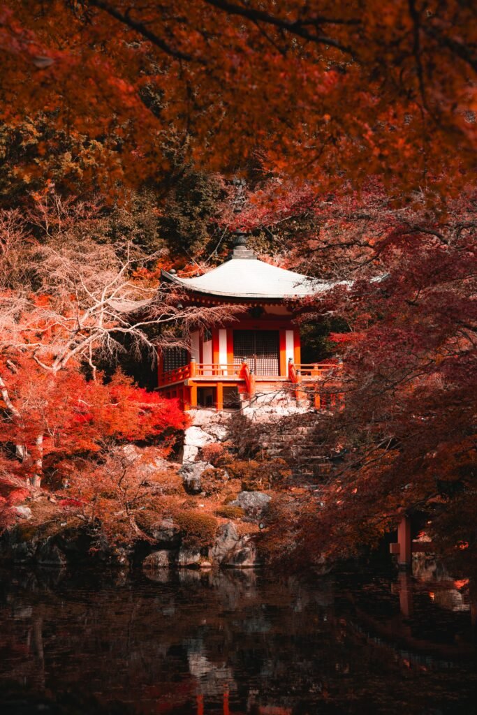 Japanese temple surrounded by vibrant autumn leaves by a pond, Kyoto